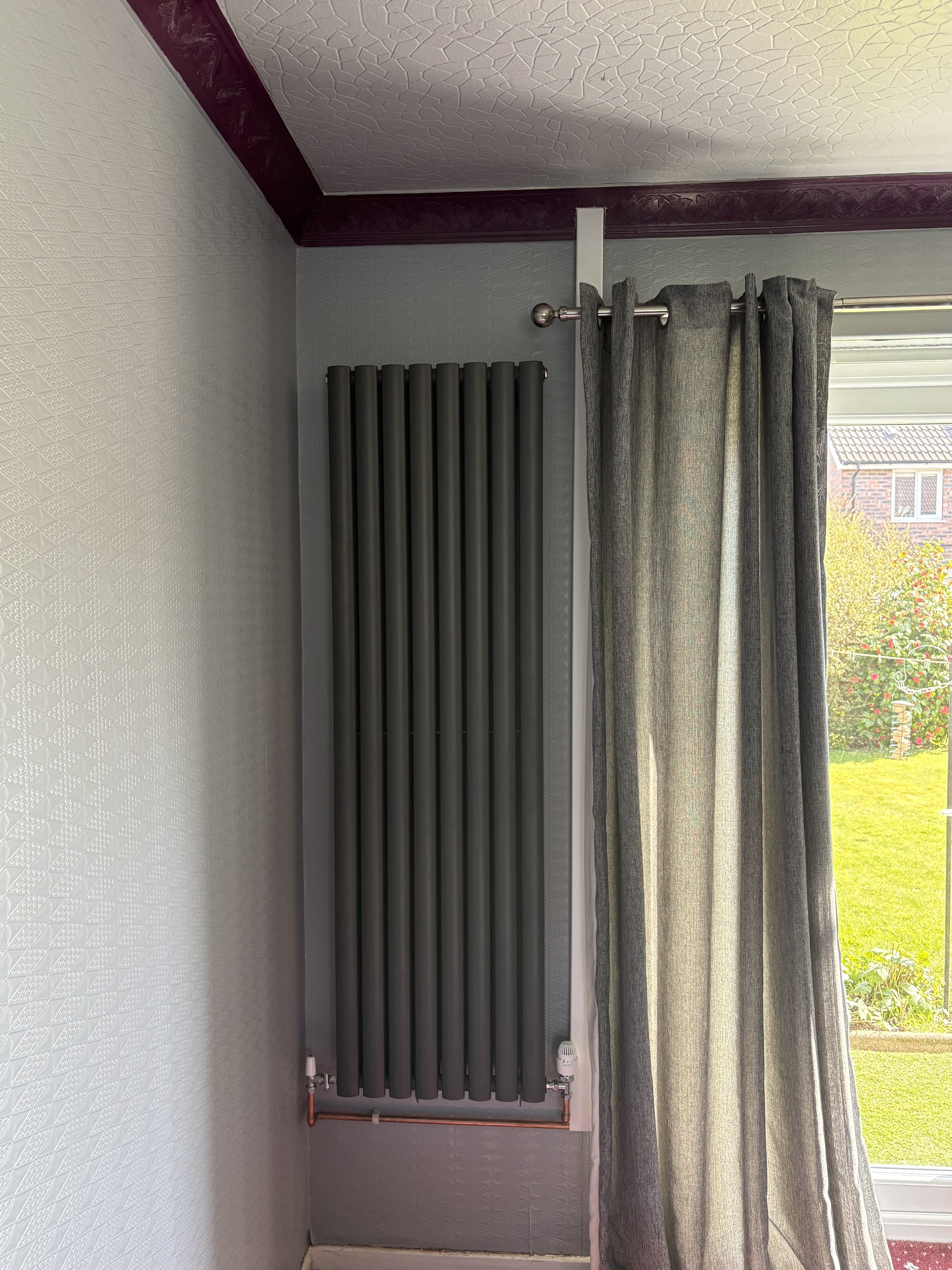 A tall vertical radiator beside a window