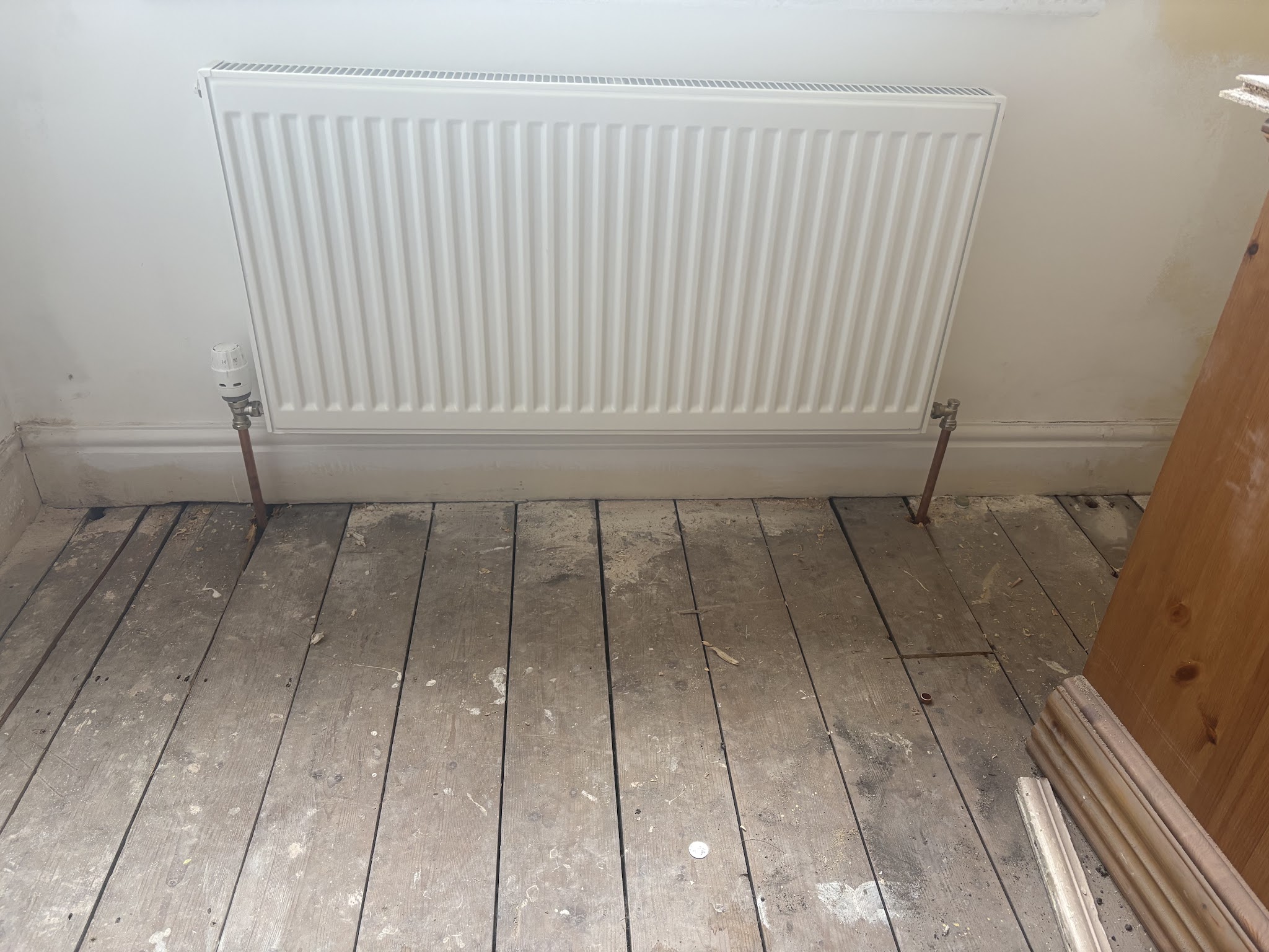 A new white panel radiator in a room being renovated